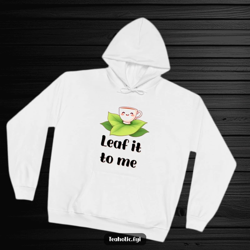 Funny teacup character smiling while floating on a large tea leaf, cozy hoodie for tea lovers.